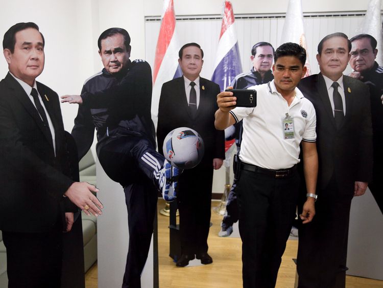 A journalist selfies with cardboard cut-outs of Thailand&#39;s Prime Minister Prayuth Chan-ocha