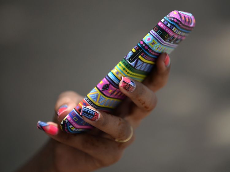 An Indian student checks her mobile phone in Mumbai on May 1, 2015. India raised a record USD17.6 billion during intense bidding on a government auction of wireless spectrum recently in one of the world&#39;s largest smartphone markets. The new spectrums for traditional voice and faster data services are seen as crucial for companies competing in the cut-throat Indian market, which has around 952 million mobile subscribers, according to figures released by India&#39;s telecoms regulator, TRAI. AFP PHOTO