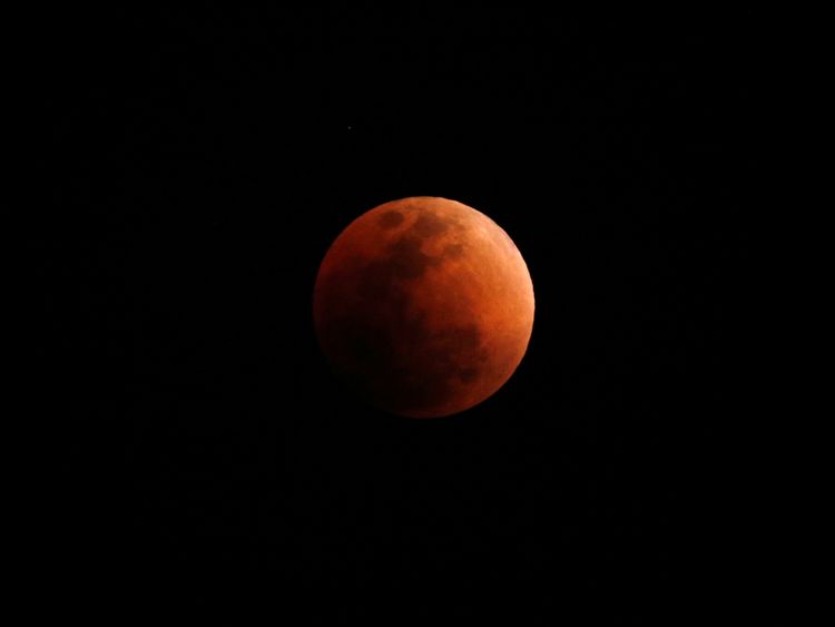 A "super blood blue moon" is seen during an eclipse, behind an office building in Hong Kong, China