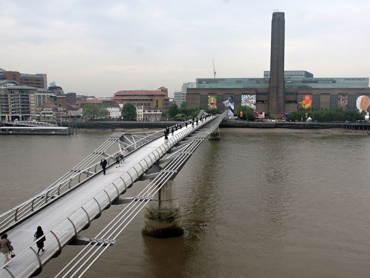 Works of art are pictured behind the Millennium Bridge on the river facade of the Tate Modern in London, on May 23, 2008. The Tate Modern commissioned six artists, whose work is intricately linked to the urban environment and unveiled the giant street art works on Friday. The artists are: Blu from Bologna, Italy; the artist collective Faile from New York, USA; JR from Paris, France; Nunca and Os Gemeos, both from Sao Paulo, Brazil and Sixeart from Barcelona, Spain. AFP PHOTO/Shaun Curry (Photo c