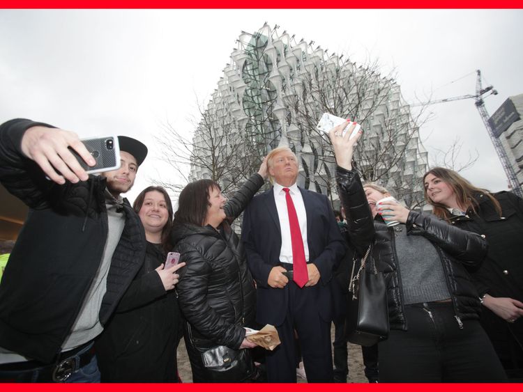 People take selfies with the Madame Tussauds wax figure of US President Donald Trump outside the new US Embassy in Nine Elms, London