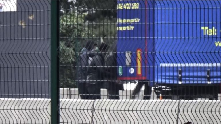 A group of teenagers huddle around the back of a lorry and get in