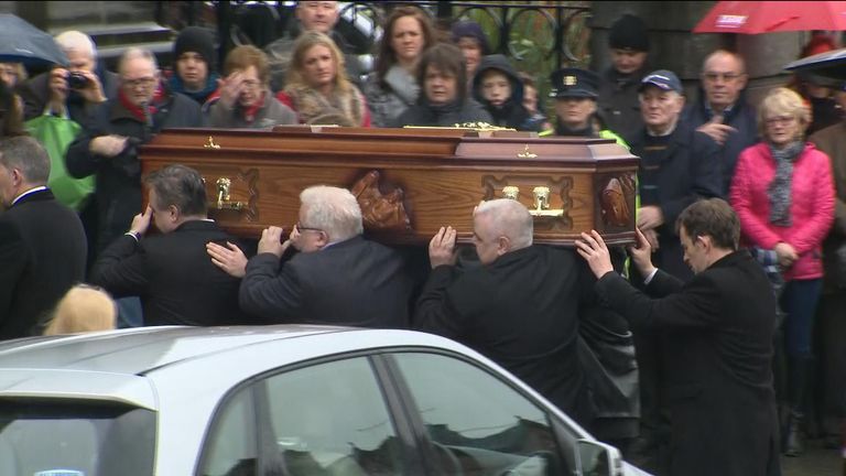The coffin being carried as mourners watch on