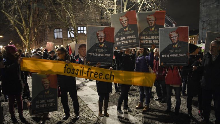 People hold up banners with the image of the US president as they protest against his attendance to the upcoming Davos World Economic Forum in central Zurich