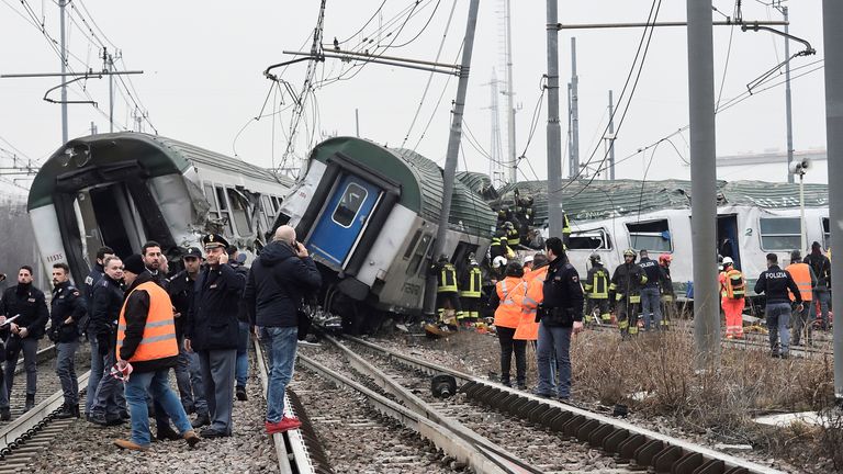 Rescue workers and police officers stand near derailed trains in Pioltello, on the outskirts of Milan, Italy, January 25, 2018