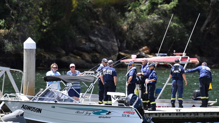 Australian Fire & Rescue personnel stand near their boats after visiting the scene where a seaplane crashed...