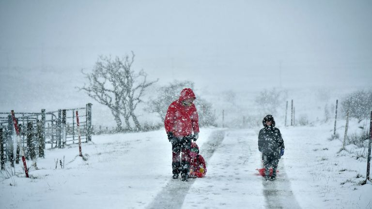 A father and his children make their way through the snow in Belfast