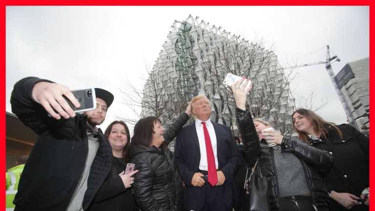 People take selfies with the Madame Tussauds wax figure of US President Donald Trump outside the new US Embassy in Nine Elms, London