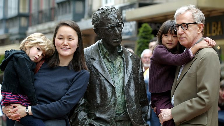 Woody Allen holds his daughter Manzie Tio as his wife Soon-Yi Previn carries daughter Bechet while they pose near a statue of Allen in Oviedo, northern Spain