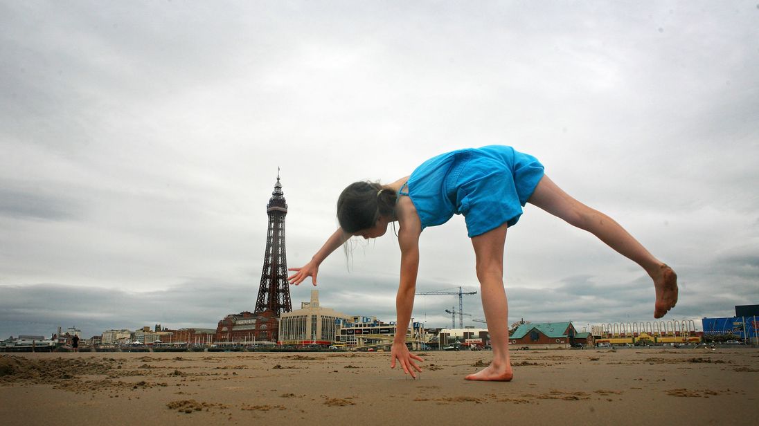 A young girl practices her gymnastics on the beach near Blackpool Tower