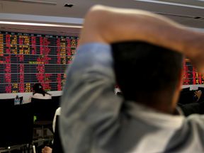People monitor a stock index board at a bank in Bangkok, Thailand