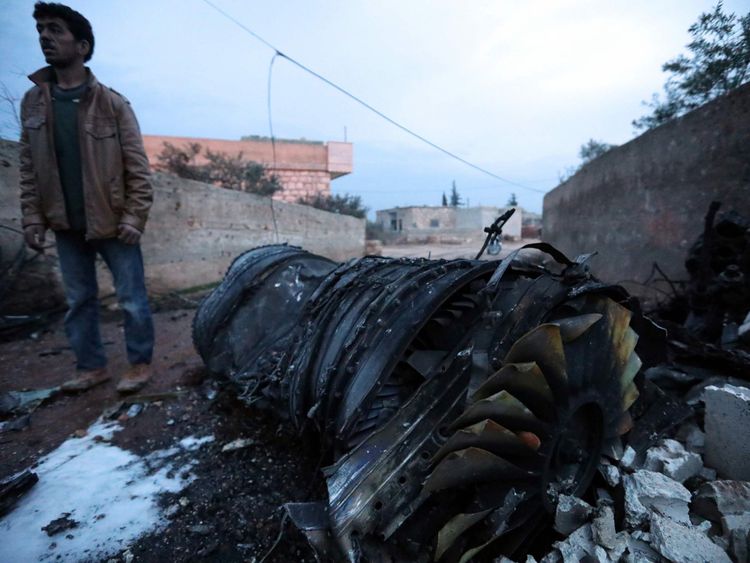 A Syrian man stands beside the engine of a shot-down Russian plane