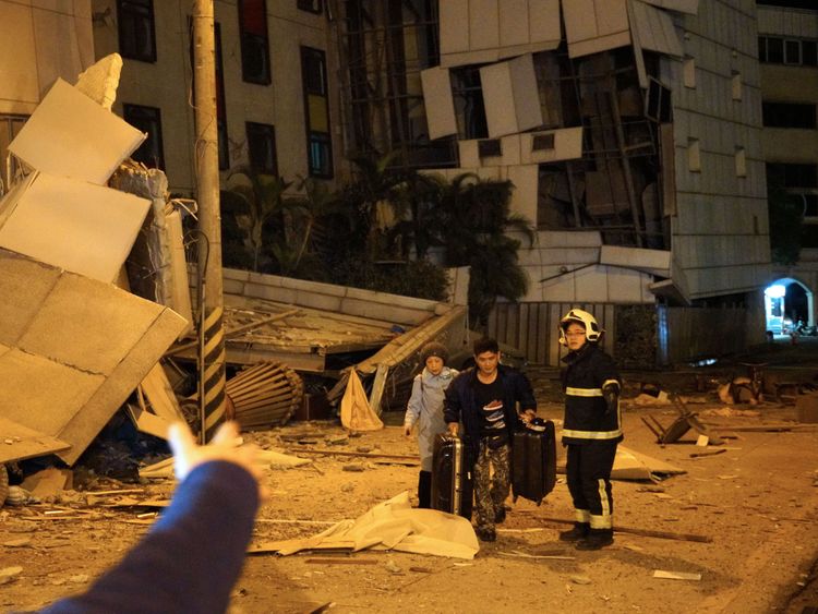 Two guests are escorted by rescue workers from the damaged Marshal Hotel in Hualien, eastern Taiwan early February 7, 2018, after a strong earthquake struck the island. A hotel on the east coast of Taiwan has collapsed after a 6.4-magnitude earthquake, the government said. / AFP PHOTO / YANG JEN-FU / Taiwan OUT (Photo credit should read YANG JEN-FU/AFP/Getty Images)