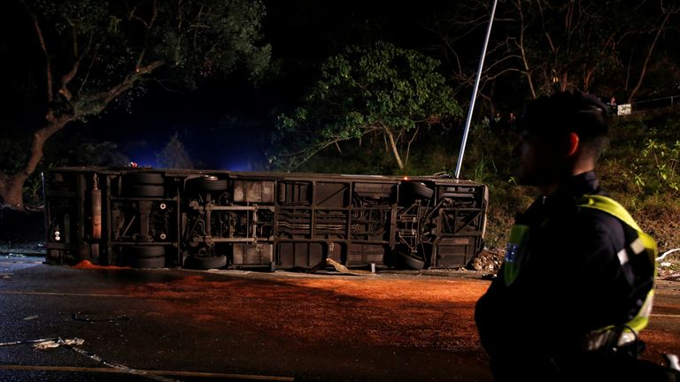 A policeman stands beside the crashed bus in Hong Kong