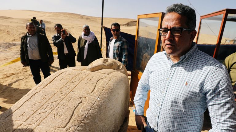 Minister of Antiquities Khaled El-Enany stands near a stone sarcophagi