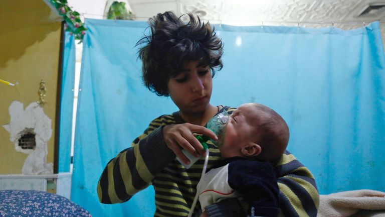 A Syrian boy holds an oxygen mask over the face of an infant following a reported gas attack on the rebel-held besieged town of Douma