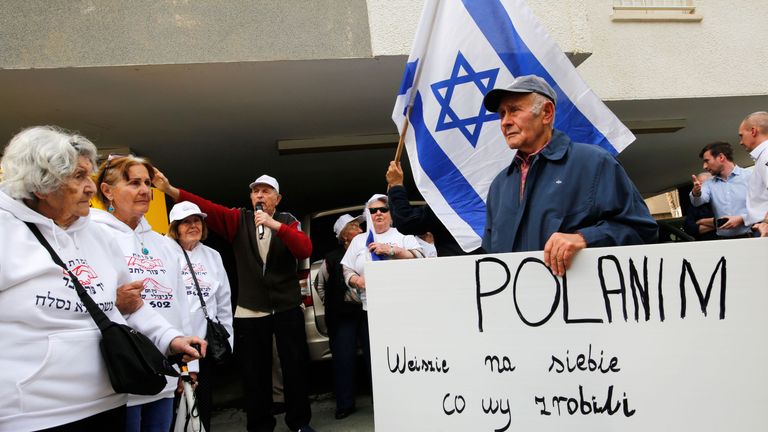 Holocaust survivors hold banners and wave an Israeli flag during a protest in front of Polish embassy in Tel Aviv on February 8, 2018, against a controversial bill passed by the eastern European country&#39;s senate. The legislation sets fines or a maximum three-year jail term for anyone describing Nazi German death camps in Poland, like Auschwitz-Birkenau, as Polish. / AFP PHOTO / GIL COHEN-MAGEN (Photo credit should read GIL COHEN-MAGEN/AFP/Getty Images)
