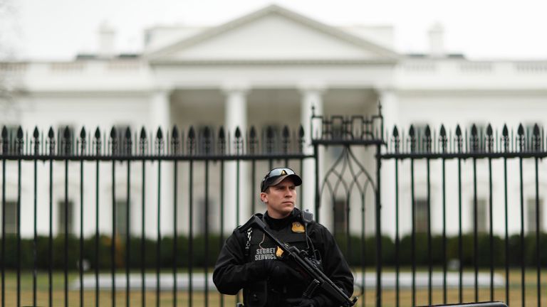 A uniformed Secret Service officer stands guard in front of the White House