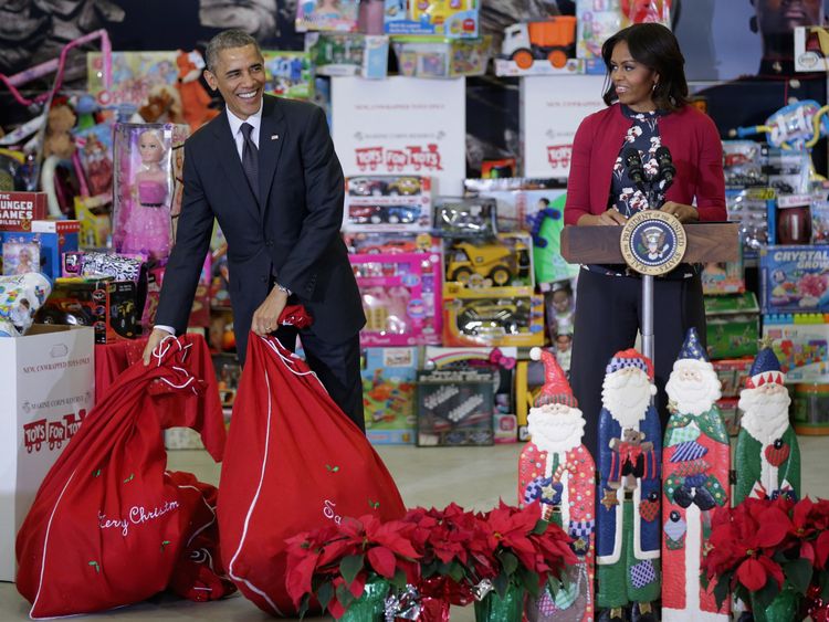 US President Barack Obama (L) sets down bags of toys as he and first lady Michelle Obama deliver gifts donated by Executive Office of the President staff to the Marine Corps Reserve Toys for Tots Program at Joint Base Anacostia-Bolling December 10, 2014 in Washington, DC. For 67 years the Toys for Tots program has worked with local communities to collect and distribute toys and gifts for less fortunate children throughout the United States