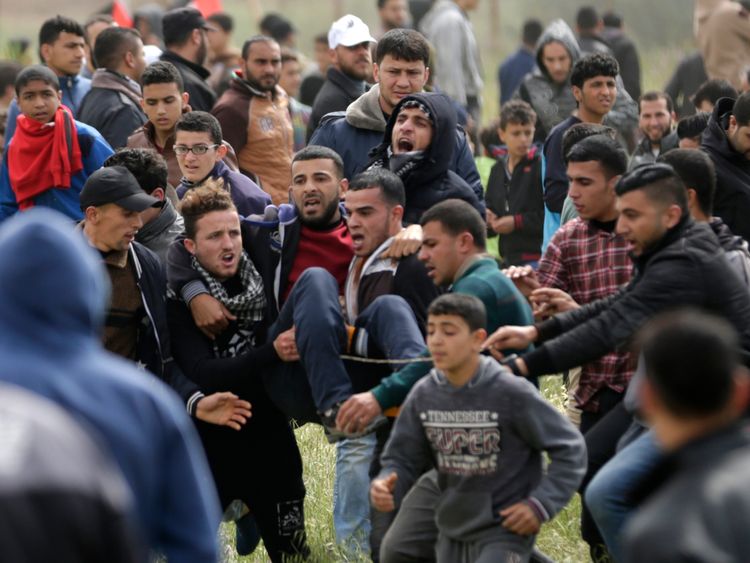 An injured Palestinian youth being carried by other protesters as they flee during clashes