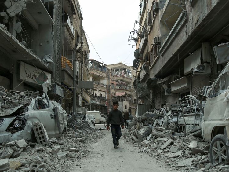 A picture taken on March 8, 2018 shows a Syrian child walking down a street past rubble from destroyed buildings, in the rebel-held town of Douma in the Eastern Ghouta enclave on the outskirts of Damascus