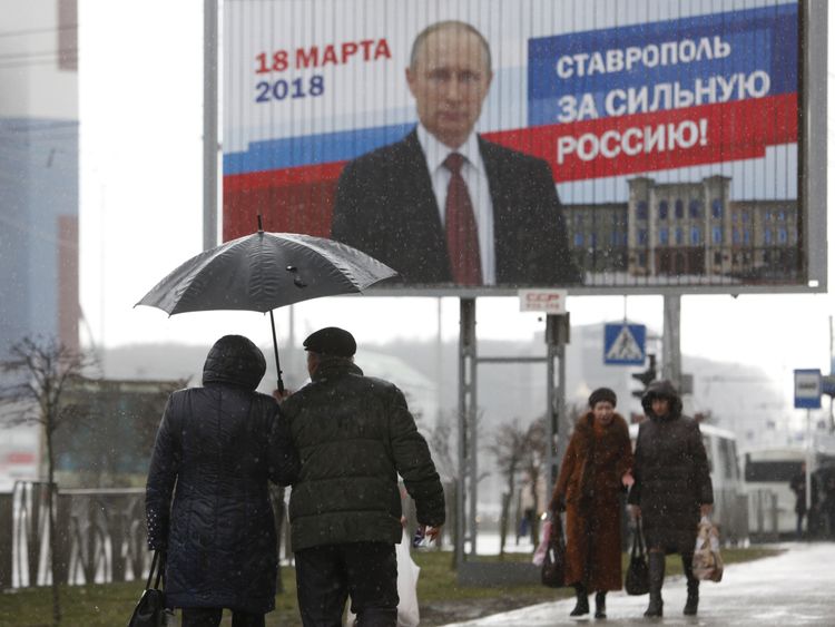 People walk next to the election campaign poster of Russian President Vladimir Putin in Stavropol, Russia March 14, 2018. The board reads "Stavropol is for strong Russia!" REUTERS/Eduard Korniyenko