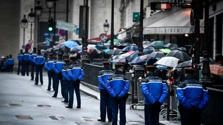 People and French gendarmes wait for the arrival of the body of Lt Col Beltrame