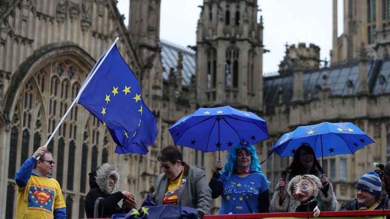 Anti-Brexit demonstrators wave European Union flags from the top deck of a bus parked outside the Houses of Parliament in London on March 29, 2018