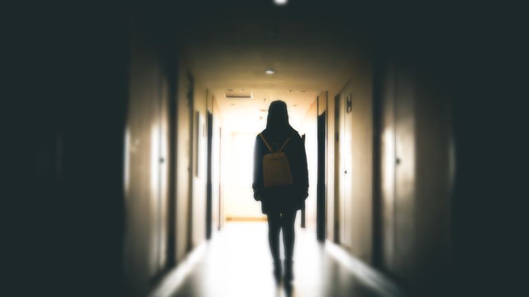 Young woman in dark building walkway - Stock image