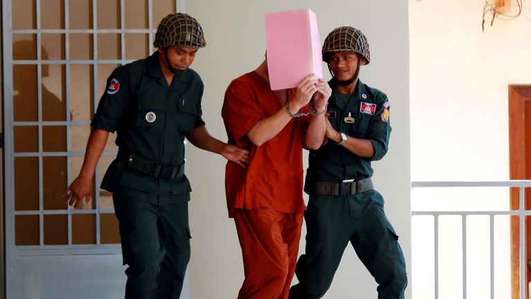 Daniel Richard Leeming Jones is escorted by police after he was found guilty of producing pornography, at the Siem Reap provincial Court, Cambodia 