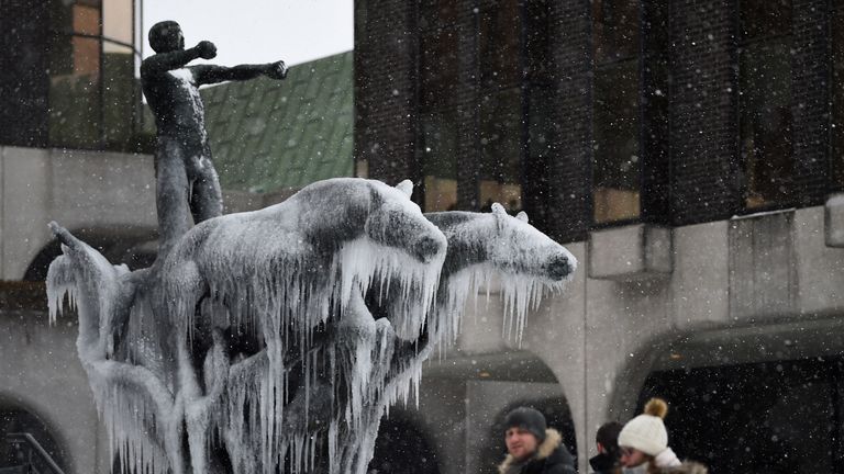 People walk past a frozen statue in Dublin