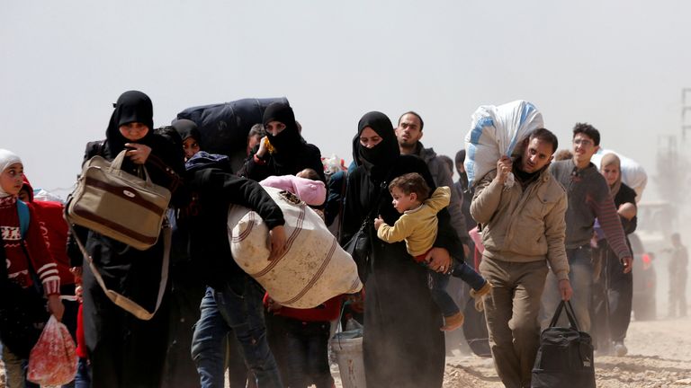People walk with their belongings as they flee the rebel-held town of Hammouriyeh, eastern Ghouta