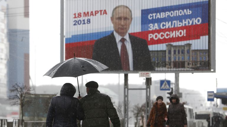 People walk next to the election campaign poster of Russian President Vladimir Putin in Stavropol, Russia March 14, 2018. The board reads &#34;Stavropol is for strong Russia!&#34; REUTERS/Eduard Korniyenko