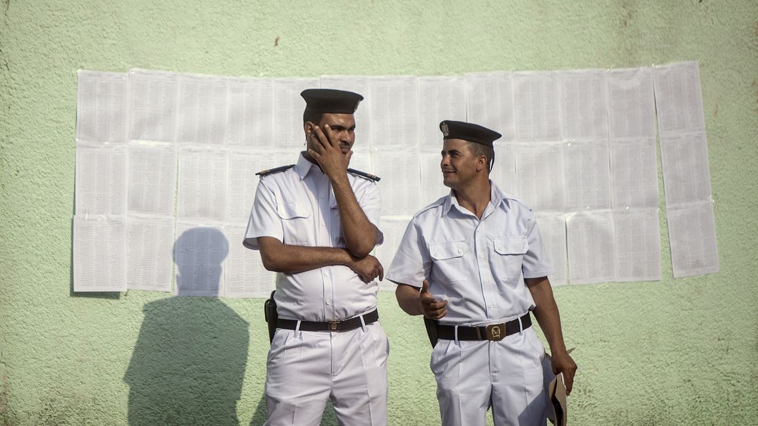 Egyptian police stand near a list of names of voters outside a polling station in Cairo on May 26, 2014