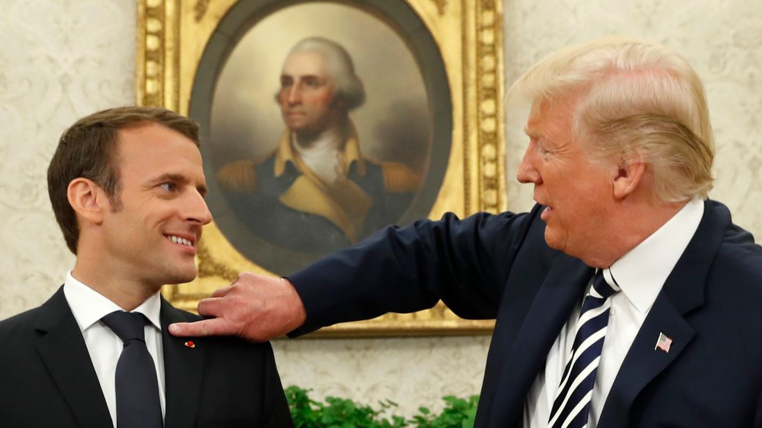 French President Emmanuel Macron (L) looks on as U.S. President Donald Trump flicks a bit of lint off his jacket during their meeting in the Oval Office following the official arrival ceremony for Macron at the White House