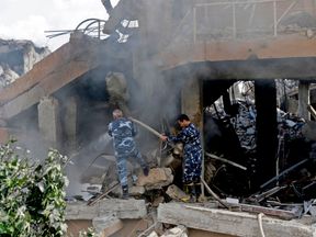 Syrian soldiers extinguish a fire in the wreckage of the part of the Scientific Studies and Research Centre in Damascus