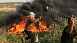 Palestinian protesters use slingshots to throw stones during clashes with Israeli forces
