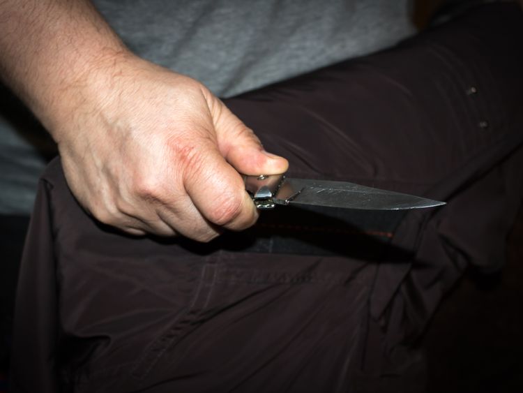STOCK PHOTO: Closeup of a young man hand, holding a knife, about to attack,