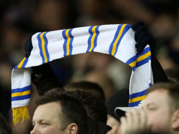 A Leeds United fan holds their scarf aloft in the stands 