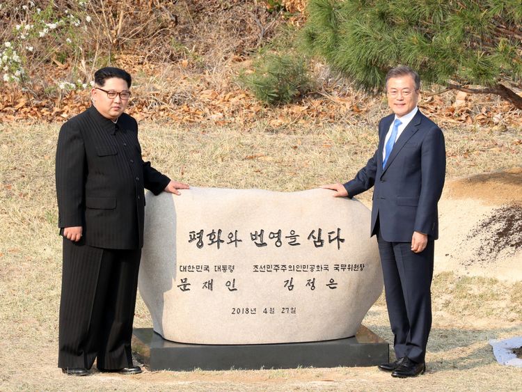 South Korean President Moon Jae-in and North Korean leader Kim Jong Un stand at a plaque after planting a commemorative tree