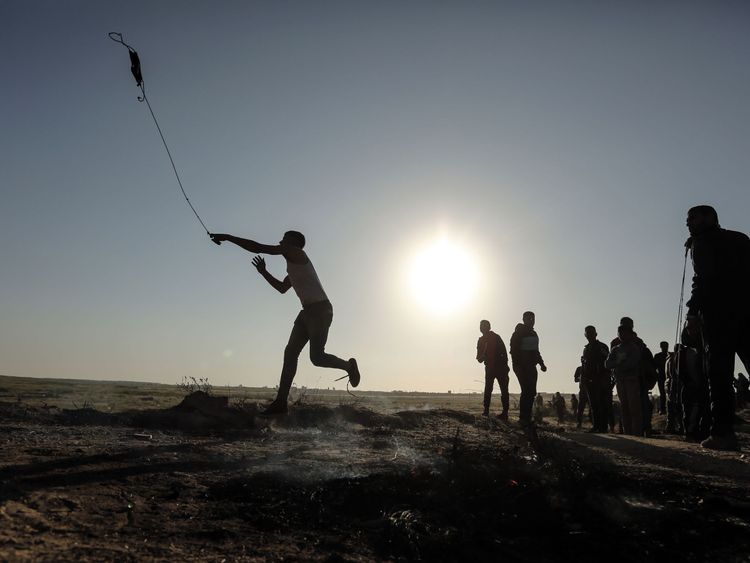 A Palestinian protester hurls stones toward Israeli soldiers 