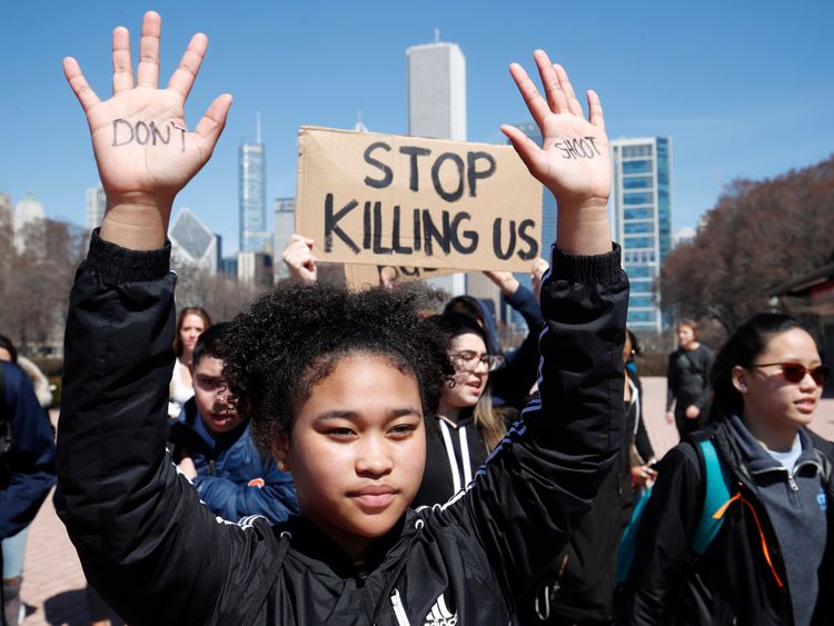A student holds up her hands while taking part in National School Walkout Day to protest school violence