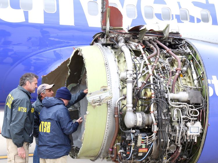 Investigators examine the damage to the plane's engine