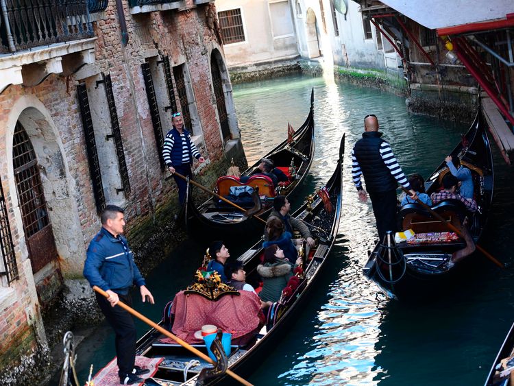 Tourists sit in gondolas on the Grand Canal in Venice