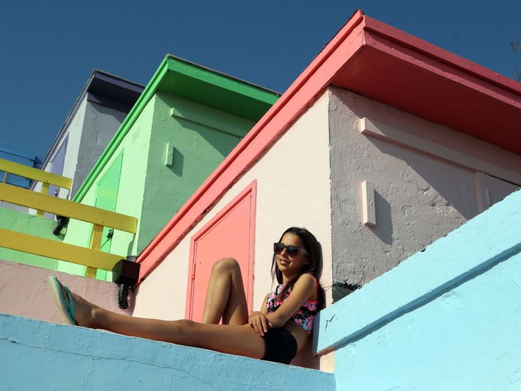 A woman enjoys the warm weather among the beach huts in Folkestone, Kent, on Friday