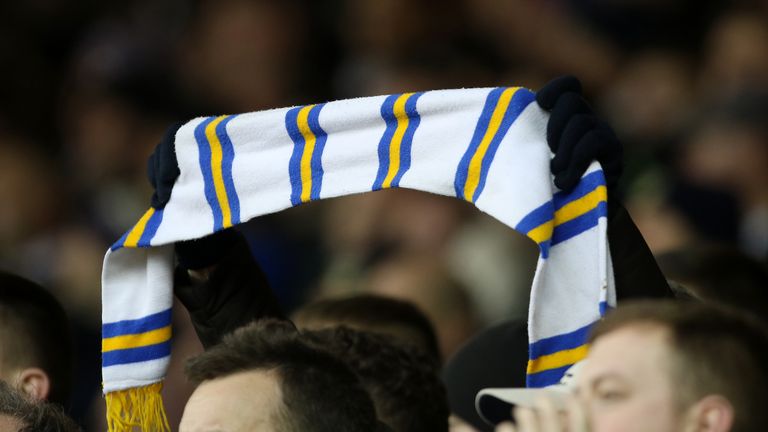 A Leeds United fan holds their scarf aloft in the stands
