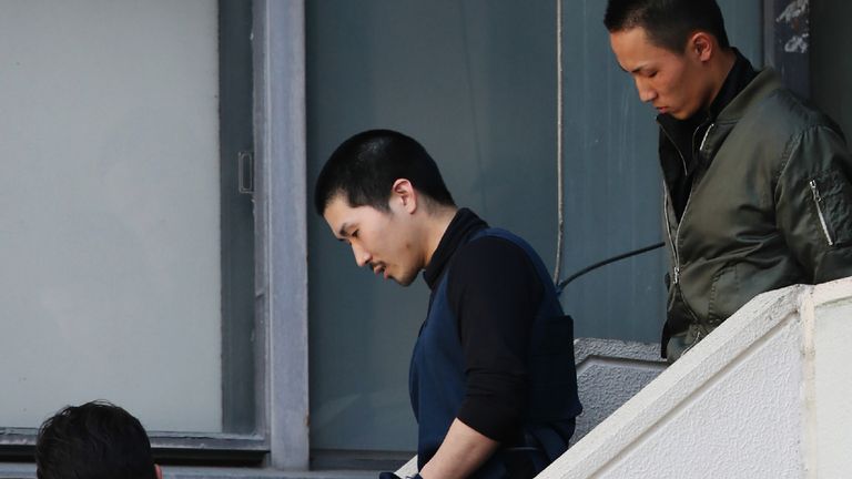 Tatsuma Hirao is escorted as he leaves a police department in Hiroshima