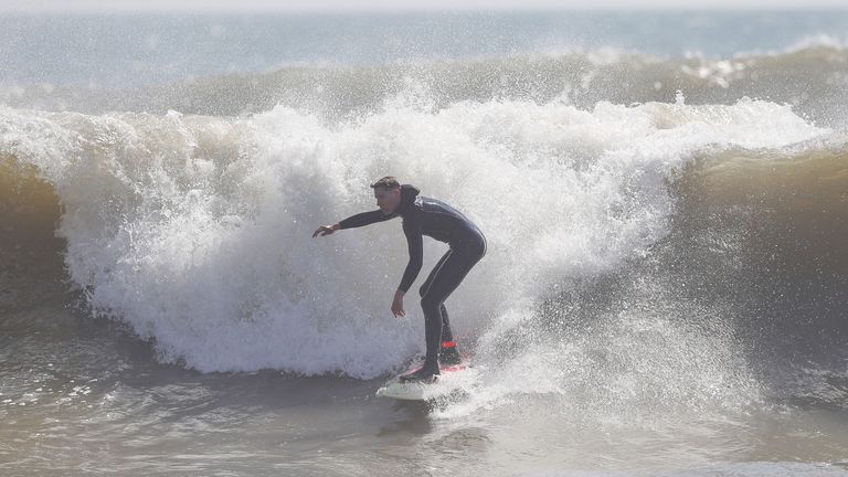 A surfer rides a wave off Boscombe Beach in Dorset