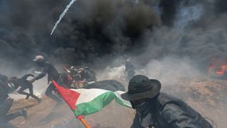 Palestinian demonstrators run for cover from Israeli fire and tear gas during a protest against U.S. embassy move to Jerusalem and ahead of the 70th anniversary of Nakba, at the Israel-Gaza border in the southern Gaza Strip May 14, 2018. REUTERS/Ibraheem Abu Mustafa 