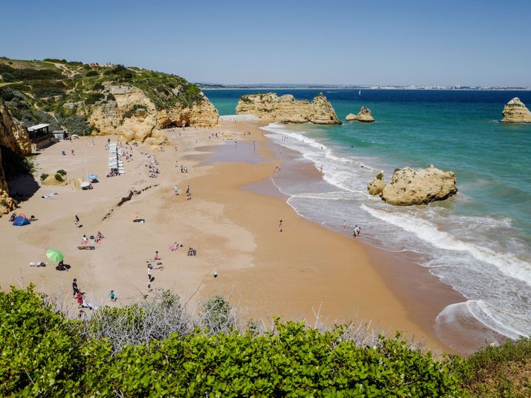People enjoy the warm weather at the Dona Ana beach in Lagos on April 18, 2018 in the southern Portugal region of Algarve